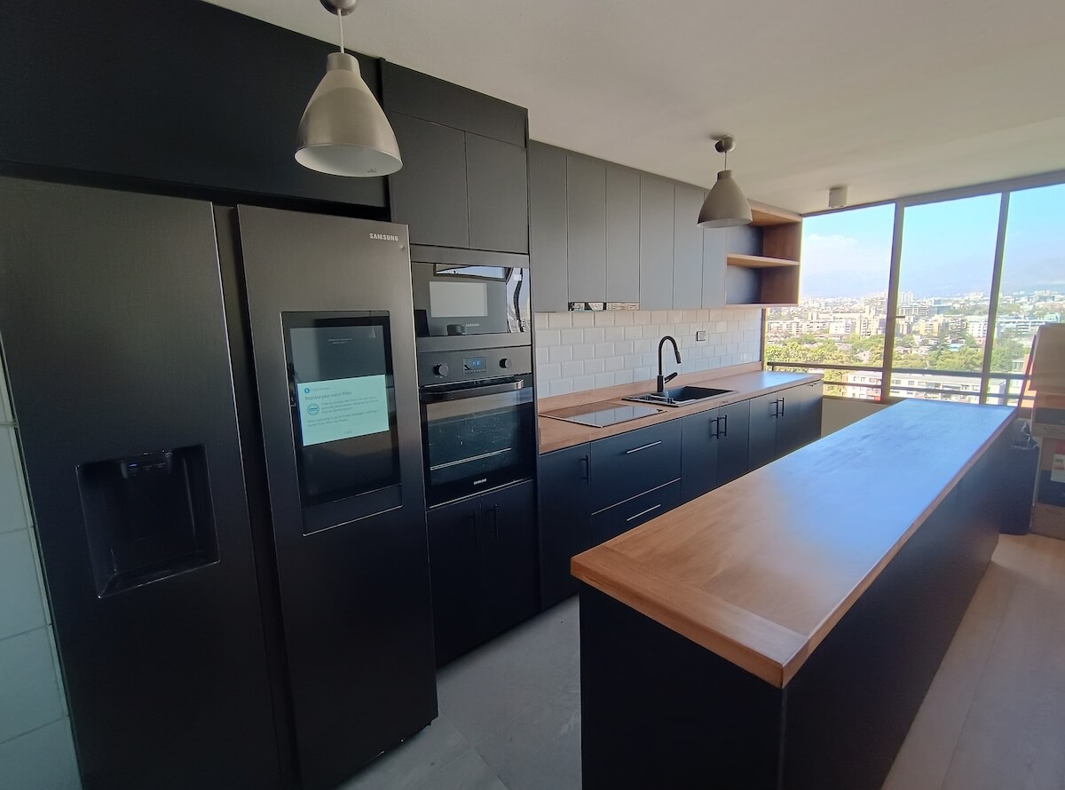 Cocina moderna con muebles negros y cubierta de madera